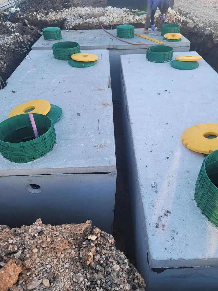 Two new concrete aerobic treatment tanks set in the ground with green risers and yellow lids