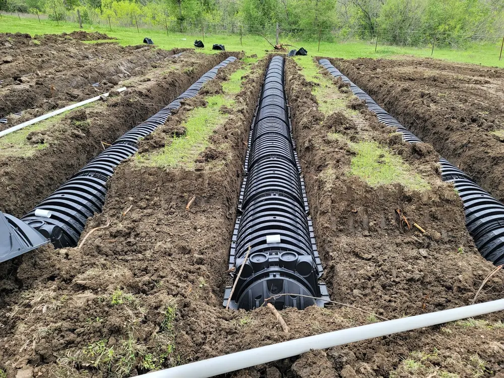 Rows of black leaching chambers laid in trenches during a drain field installation