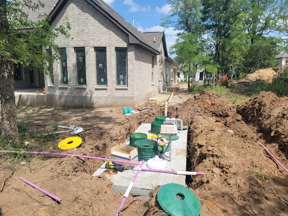 A new aerobic septic system being installed beside a stone house, with colored lids and fresh piping